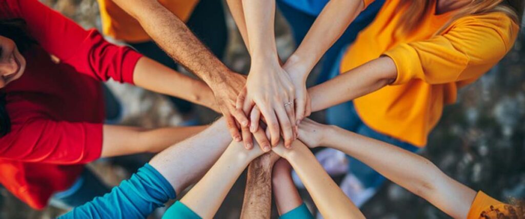 A group of people placing their hands in the centre of a circle showing teamwork.